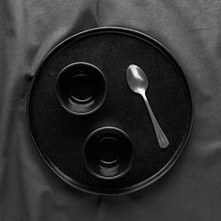 Silver spoon on a black tray with two small black bowls