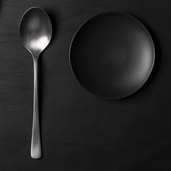 Silver spoon next to a black dessert plate